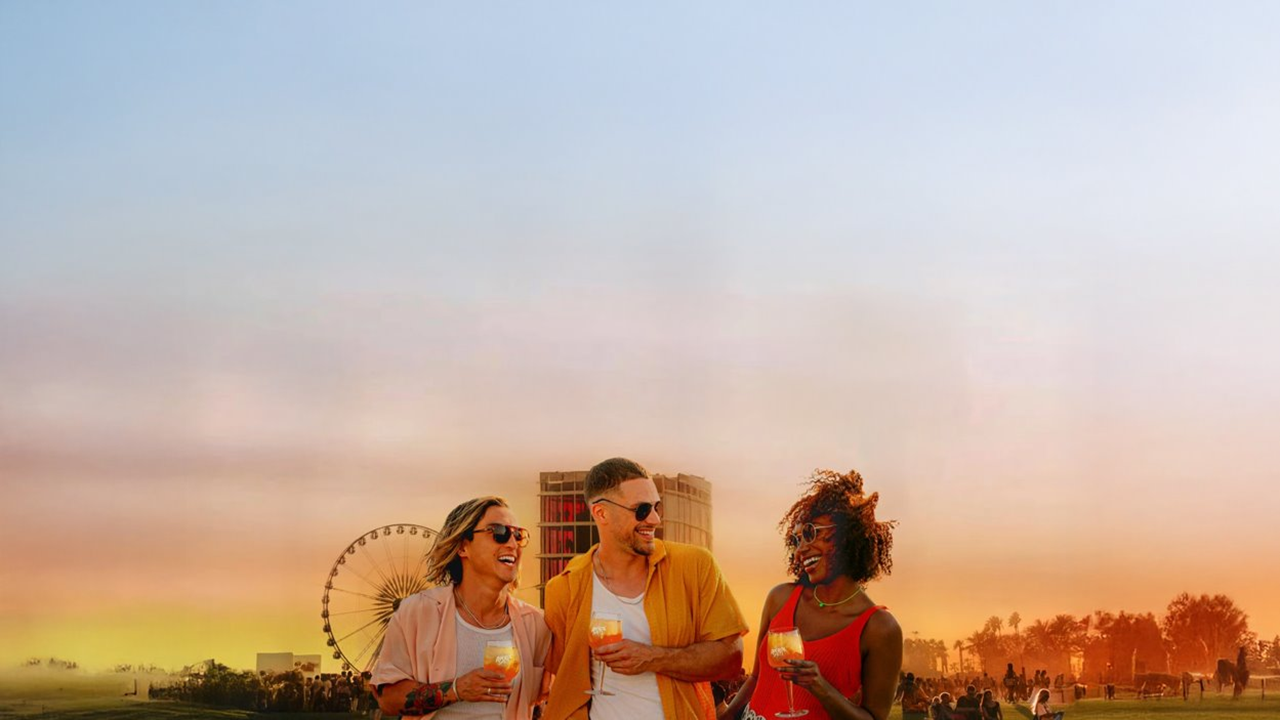 three people holding Aperol drinks at a festival