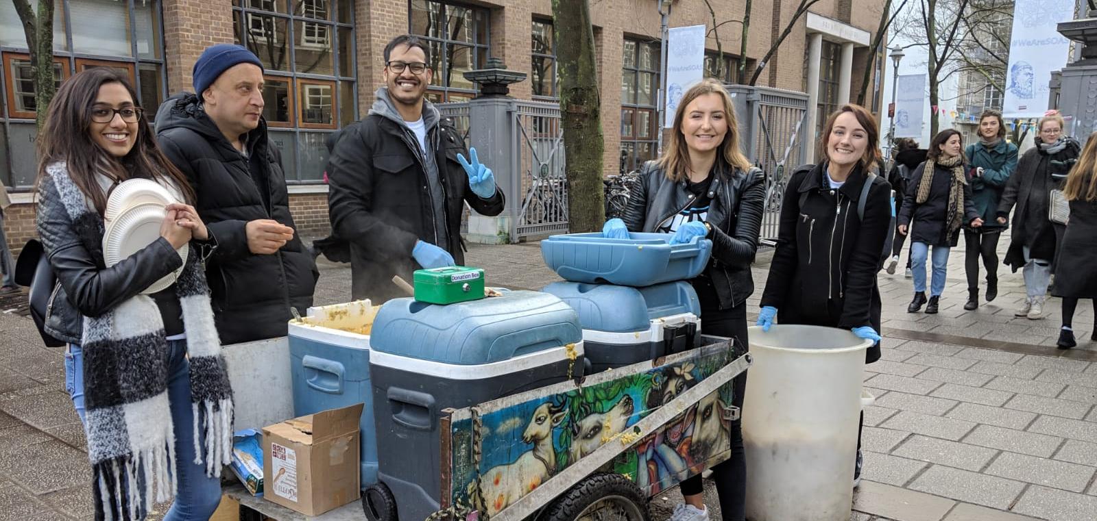 Photo of a few people by a food cart.